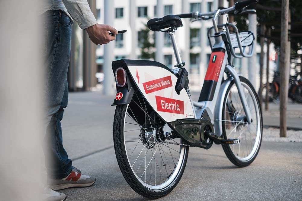 WienMobil Rad E Bike von nextbike an einer Station, ein Mann entsperrt es mit dem Smartphone