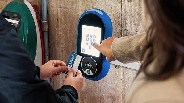 Fahrgäste halten den südtirolmobil Pass an ein blaues Entwertungsgerät