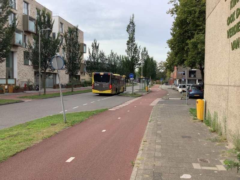 Roter, baulich getrennter Radweg neben einer Straße mit Bus in den Niederlanden